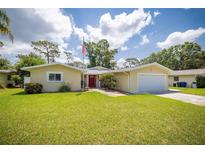 Charming single-story home with a well-maintained lawn, an American flag, and a welcoming red front door at 1891 Harmony Dr, Clearwater, FL 33756