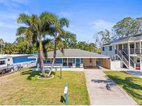 Charming single-story home with a well-manicured lawn, tall palm trees, and a long driveway at 306 12Th Ave, Indian Rocks Beach, FL 33785