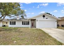 Charming one-story home with white exterior, dark shutters, and well-manicured lawn at 8737 Beaver Ln, Port Richey, FL 34668