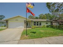 Charming single-story home featuring a well-manicured lawn, stone accents, and attached garage at 9930 121 N St, Seminole, FL 33772