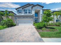 Beautiful home exterior featuring a two-car garage, brick driveway, and manicured landscaping at 10945 Sundrift Dr, Tampa, FL 33647