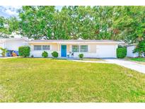 Charming single-story home featuring a bright blue front door, well-manicured lawn and attached garage at 1433 Spring Ln, Clearwater, FL 33755
