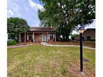Charming brick home with a well-maintained lawn and mature trees, offering a cozy curb appeal at 35058 Whispering Oaks Blvd, Dade City, FL 33523