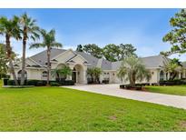 Stately single-story home boasts a manicured lawn, complemented by mature palm trees and a circular driveway at 5182 Championship Cup Ln, Spring Hill, FL 34609