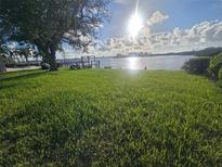Lush green backyard leading to a waterfront with a private dock at 5688 Oakhurst Dr, Seminole, FL 33772