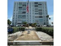 Multi-story condo building with manicured landscaping and an American flag, set against a clear blue sky at 7200 Sunshine Skyway S Ln # 2E, St Petersburg, FL 33711