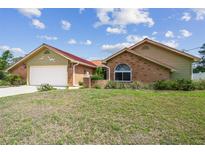 Single-story home featuring brick accents, light yellow siding, and a well-manicured front yard at 12371 Talpa St, Spring Hill, FL 34608