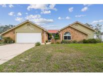 Charming single-story home featuring brick accents, light yellow siding, and a well-manicured front yard at 12371 Talpa St, Spring Hill, FL 34608