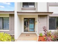 Inviting front entrance with blue screen door and tiled entryway, enhanced by exterior landscaping at 1815 Cypress Trace Dr, Safety Harbor, FL 34695