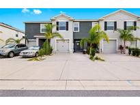 Well-maintained townhome featuring a manicured lawn and attached garage at 2906 Boxwood Grove Row, Wesley Chapel, FL 33543