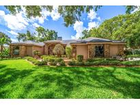 Charming single-story home with lush front lawn and manicured landscaping under a cloudy blue sky at 2963 Cielo N Cir, Clearwater, FL 33759