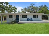 Charming single-story home featuring a well-maintained lawn, blue door, and an inviting front porch with two chairs at 608 Betmor Ln, Palm Harbor, FL 34683