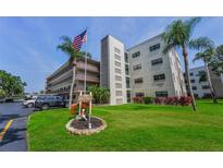 Well-maintained exterior of building, featuring an American flag, sign, palm trees, and attractive landscaping at 6190 80Th N St # 411, St Petersburg, FL 33709