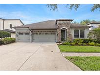 Charming home featuring a three-car garage, stone accents, and neatly landscaped front yard at 8015 Hampton Glen Dr, Tampa, FL 33647