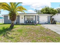 Charming home featuring a well-manicured lawn, a palm tree and a cozy front porch at 9126 Greenbriar Ln, Port Richey, FL 34668
