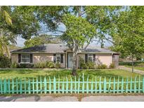 Charming single-story home with lush lawn, mature trees and adorable decorative picket fence at 1021 15Th St, Palm Harbor, FL 34683