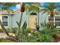 Charming home featuring a bright yellow front door surrounded by lush landscaping and beautiful palm trees at 500 Westborough Ln, Safety Harbor, FL 34695