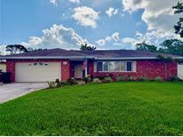Charming red brick home featuring a lush green lawn, attached garage, and beautiful landscaping at 5201 Denver Ne St, St Petersburg, FL 33703