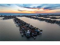 Expansive aerial view captures a waterfront community at sunset, showcasing stunning oceanfront property with pools and private docks at 5409 Pali Way, St Pete Beach, FL 33706