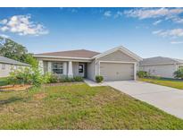 Attractive single-story home features a two-car garage, front yard landscaping, and a well-maintained lawn at 6937 Gideon Cir, Zephyrhills, FL 33541
