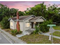 Charming home featuring a brick chimney, a small porch, and mature trees surrounding the property at 702 W Virginia Ave, Tampa, FL 33603