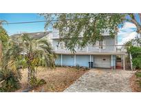 Three-story waterfront home shows balconies, garage access, and tropical landscaping in the yard at 13918 Raie Ave, Hudson, FL 34667
