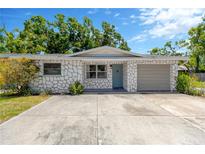 Charming single-story home with stone accents, a well-maintained lawn, and a concrete driveway leading to an attached garage at 1726 York S St, Gulfport, FL 33707