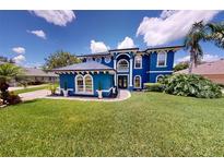 Bright blue two-story home featuring a well-manicured lawn and ornate architectural details at 19620 Eagle Crest Dr, Lutz, FL 33549