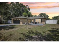 Charming single-story home features a well-manicured lawn, two palm trees, and a cozy outdoor seating area at 911 S Florida Ave, Tarpon Springs, FL 34689