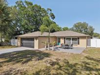 Charming single-story home featuring a gray garage door and quaint outdoor seating area at 911 S Florida Ave, Tarpon Springs, FL 34689