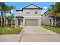 Two-story home featuring a two-car garage, well-maintained lawn, and tasteful landscaping with palm trees at 9640 Lemon Drop Loop, Ruskin, FL 33573