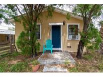 Charming home featuring a vibrant blue front door, complemented by a matching blue chair, creating a welcoming entrance at 1142 7Th Nw St, Largo, FL 33770