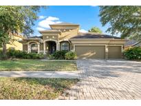 Beautifully landscaped home with brick driveway, manicured lawn, and inviting curb appeal at 15104 Azra Dr, Odessa, FL 33556