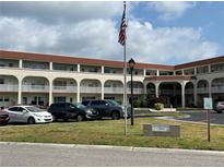 A sunny exterior view of the building with a flag in the front and multiple cars parked outside at 2434 Australia E Way # 50, Clearwater, FL 33763