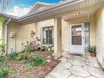 Inviting front entrance featuring a textured walkway and garden area with plants leading to the front door at 120 Colony South Dr, Tarpon Springs, FL 34689