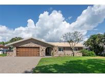 Charming single-story home with a brick and light-colored exterior, a well-manicured lawn and a two-car garage at 2017 Iowa Ne Ave, St Petersburg, FL 33703
