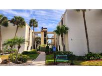 Inviting condo exterior with lush landscaping, mature palm trees, and accessible parking in a serene setting at 2205 Belleair Rd # A36, Clearwater, FL 33764