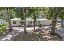Charming single-story home with mature trees and a well-manicured front yard, painted a clean bright white at 2353 Dora Dr, Clearwater, FL 33765