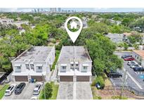 An aerial view of two modern townhomes with a paved driveway and parking, located in a lush, green community near the city at 308 S New Jersey Ave # A, Tampa, FL 33609