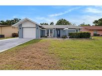 Charming single-story home featuring a well-maintained lawn, attached garage, and cozy front porch seating area at 4326 Great Lakes N Dr, Clearwater, FL 33762