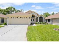 Charming single-story home featuring a two-car garage, well-manicured lawn, and inviting front entrance at 521 Bent Oak Ct, Spring Hill, FL 34609