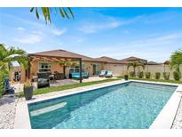 Sparkling pool with poolside lounge area and covered outdoor kitchen perfect for entertaining at 7114 Fern Garden Ct, Sun City Center, FL 33573