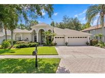 Charming single-story home featuring a three-car garage, paver driveway, manicured lawn and lush landscaping at 17318 Emerald Chase Dr, Tampa, FL 33647