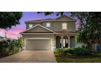 Charming two-story home featuring a two-car garage, landscaped yard, and covered entryway with arched columns at 4717 W Lawn Ave, Tampa, FL 33611