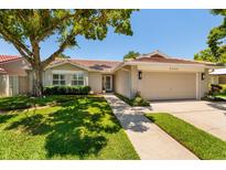 Charming home featuring a well-maintained lawn, a red tile roof, and a two-car garage at 5242 Venice Ne Way, St Petersburg, FL 33703