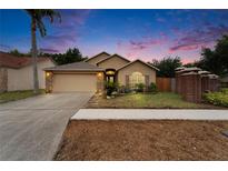 Charming single-story home with a well-manicured lawn and inviting curb appeal at dusk at 6801 Bishops Pointe Way, Riverview, FL 33578