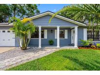 Charming home with a brick facade, white columns, and lush landscaping at 8307 Boxwood Dr, Tampa, FL 33615