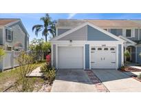 Charming townhome featuring a well-maintained facade with attached garages and landscaped surroundings at 12307 Villager Ct, Tampa, FL 33625
