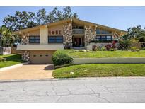 Charming two-story home with stone facade, mature trees, and well-manicured lawn offers curb appeal at 2287 Demaret Dr, Dunedin, FL 34698