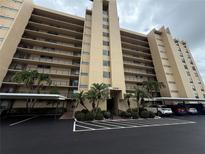 An exterior view of a multi-story residential building featuring parking and palm tree landscaping at 2621 Cove Cay Dr # 206, Clearwater, FL 33760